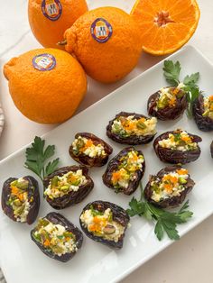 an assortment of appetizers on a white plate next to oranges