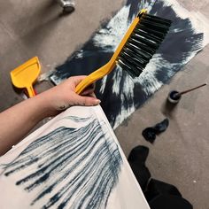 a person holding a paintbrush over a piece of art