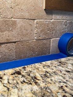 a roll of blue tape sitting on top of a counter next to a brick wall