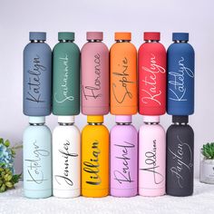 six different colored water bottles with the names of each one on them, all lined up in a row