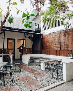 an outdoor seating area with tables and chairs in front of a building that has a wooden fence