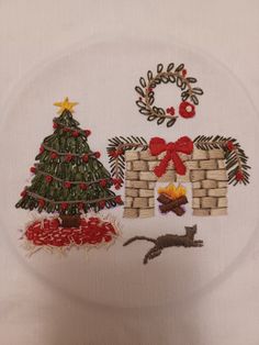 a white plate with a christmas tree and other decorations on it, sitting next to a cat