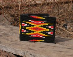 a small beaded wallet sitting on top of a wooden table next to some branches