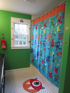 a bathroom decorated in green and orange with monster themed shower curtain, rug, and window