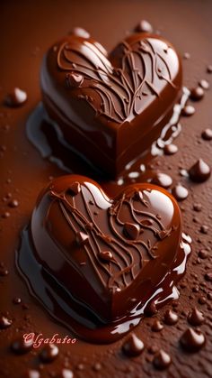 two heart shaped chocolates sitting on top of a table covered in melted chocolate drops