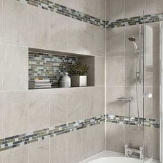 a bath tub sitting under a window next to a tiled wall and shower head in a bathroom