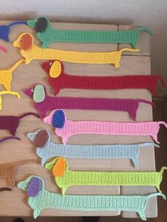 several crocheted dachshunds are displayed on a wooden board with scissors