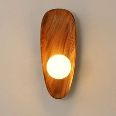 a wooden wall light with a white light in the middle on a gray background,