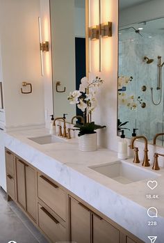 a bathroom with double sinks and large mirrors on the wall above them is illuminated by lights