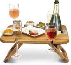 two glasses of wine are sitting on a wooden table with food and drinks in front of them