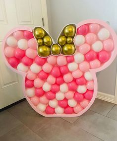 a mickey mouse balloon decoration with gold and pink balloons in the shape of a head