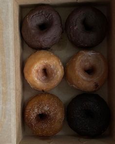 six donuts in a cardboard box with chocolate and sprinkles on them