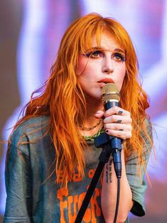 a woman with red hair holding a microphone