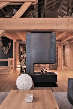 a living room with wood floors and a fireplace in the center, surrounded by wooden beams