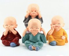 three small buddha figurines sitting next to each other with their hands on their faces