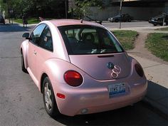 the pink car is parked on the side of the road