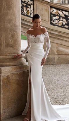 a woman in a white wedding dress leaning against a pillar