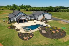 an aerial view of a large house with a pool in the front yard and landscaping around it