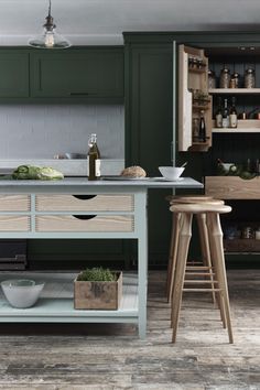 a kitchen with green cabinets and wooden stools