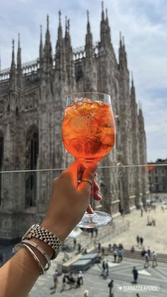 a person holding up a wine glass in front of a building