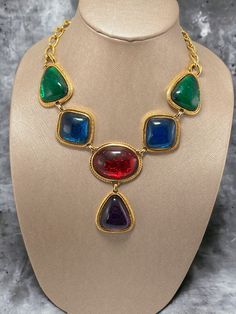 "Of course this would be a masterpiece by Kenneth J Lane This is the necklace from the Caprianti collection by KJL. This necklace showcases jewel-tone \"jelly belly\" cabochons that mimic those from the House of Gripoix. The cabochons are made of translucent jewel-tone colored Lucite, which lets the textured metal within allow them to appear to shimmer. This necklace is shown in the book \"SHAMELESSLY: Jewelry from Kenneth J Lane\" by Nancy Schiffer on page 192. Hallmark:  KJL for Avon Measures: Elegant Multicolor Cabochon Necklaces, Multicolor Cabochon Costume Jewelry, Vintage Multicolor Cabochon Jewelry, Formal Costume Jewelry Necklace With Cabochon, Formal Cabochon Costume Jewelry Necklace, Metal Cabochon Necklace In Costume Jewelry Style, Multicolor Costume Jewelry Necklace For Collectors, Multicolor Metal Necklaces For Collectors, Jewel Tone Colors