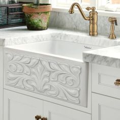 a white kitchen sink sitting under a window next to a potted plant on top of a counter