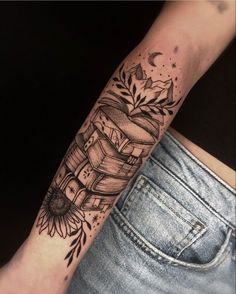 a woman's arm with a tattoo on it that has books and flowers on it