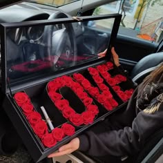 a woman sitting in the back seat of a car holding a box with roses on it