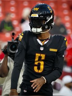 a football player wearing a black uniform and holding a camera