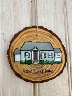 a home sweet home ornament hanging on a wood slice with the words home sweet home painted on it