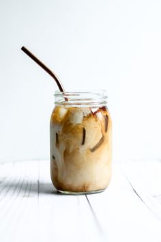 a glass jar filled with liquid and topped with a brown straw sticking out of it