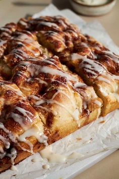 cinnamon rolls with icing sitting on top of paper