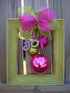 a pink ornament hanging from a wooden frame with a bow and number on it