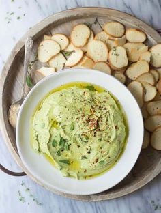 a bowl of hummus and crackers on a plate