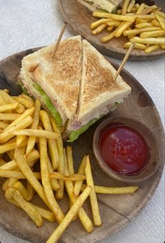 two plates with sandwiches and french fries on them