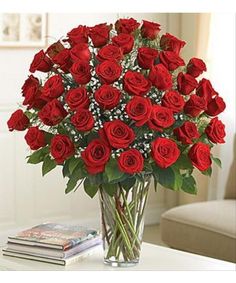 a vase filled with red roses sitting on top of a table next to a book