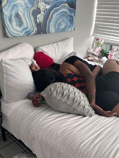 two people laying on top of a bed next to each other