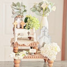 a table topped with vases filled with flowers and greenery on top of it