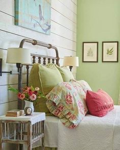 a bedroom with green walls, white bedding and pink pillows on the headboard