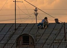 two people sitting on the roof of an old building