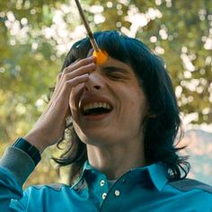 a man with long hair holding an umbrella up to his face and laughing at the camera