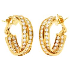 Inside/outside style earrings are designed as three twisting bands with round brilliant cut diamonds. Bead set in recessed channels and weighing approximately 6.15 carats total. F/G in color with VS clarity. Completed by posts with hinged omega backs. With French hallmarks for 18 karat gold. Numbered and fully signed Cartier. Circa: 1990's from the Trinity collection. Measures: 3/8 x 1 1/8 inches. Total weight: 24.5 grams. Interlocking. Eternal. Glitz. Stock Number: We-10077 Trinity Earrings, Bead Set, Inside Outside, Style Earrings, Round Brilliant Cut Diamond, Brilliant Cut Diamond, Round Brilliant, Cartier, Interior Exterior