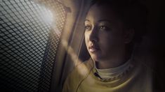 a woman is looking out the window at something in the air with light shining on her face