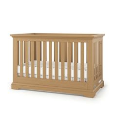 a wooden crib with white sheets on the bottom and side rails, in front of a