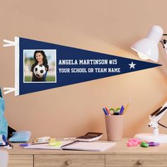 a desk with a laptop and a soccer ball on it, next to a personalized pennant