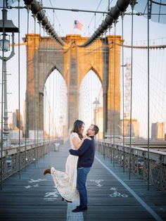 an engaged couple standing on the brooklyn bridge