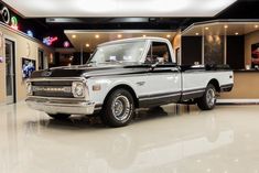 an old black and white truck in a showroom with neon signs on the walls