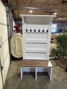 a white bench with coat hooks on it in a storage room next to other items