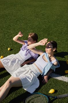 two women laying on the ground with tennis rackets