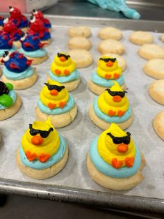 there are many decorated cookies in the shape of little yellow ducks on top of each other